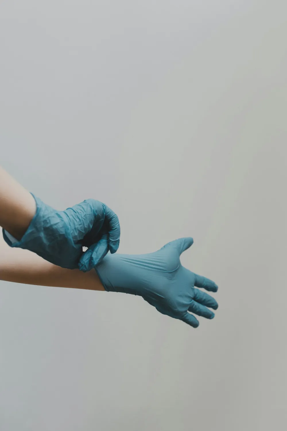 Medical professional putting on blue nitrile gloves before a cosmetic treatment